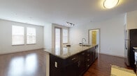 This single-floor residence offers a thoughtfully designed open-concept layout that seamlessly connects the kitchen and living areas. The kitchen serves as the centerpiece of the space, anchored by a large island with granite countertops, an integrated sink, and dark espresso cabinetry with brushed hardware. Stainless steel appliances, including a refrigerator, range, and microwave, complement the classic white subway tile backsplash, creating a clean and modern aesthetic. Rich hardwood flooring extends throughout the main living area, which is bathed in natural light from multiple windows and a glass-paneled door.

The bedrooms are finished with plush wall-to-wall carpeting and feature wide windows with blinds that allow for ample natural light while maintaining privacy. Each room offers a versatile, open canvas ideal for a variety of furniture arrangements.

The bathrooms continue the upscale material palette with granite vanity tops, dark wood cabinetry, and chrome fixtures. The full bathroom includes a tiled tub-and-shower combination with warm-toned tile work, while a half or secondary bath provides an additional granite-topped vanity. The consistent use of quality finishes throughout creates a cohesive and refined ambiance across the entire residence.