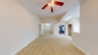 This thoughtfully designed residence offers a welcoming layout across a single floor, enhanced by impressive vaulted ceilings that lend a sense of openness and volume to the main living areas. Ceiling fans with integrated lighting fixtures are installed throughout, contributing to both comfort and functionality. The spacious living room features plush carpeting and connects seamlessly to a dining area illuminated by an elegant chandelier, creating a natural flow for everyday living and entertaining.

The kitchen is outfitted with rich, dark espresso-toned cabinetry, granite-style countertops, and black appliances including an electric range and refrigerator, offering both style and practicality. Hard-surface flooring in the kitchen and bathroom provides contrast to the soft carpet found throughout the rest of the home.

The bedrooms are generously sized, each featuring neutral-toned walls, carpeted floors, and ample closet space with bifold doors. The primary bedroom benefits from a ceiling fan, a walk-in closet, and direct access to a full bathroom equipped with a shower-tub combination. Additional bedrooms are bright, with windows that invite natural light and views of surrounding greenery.

A carpeted staircase with a white handrail leads to an upper loft-style area featuring vaulted ceilings, an arched window, and an open closet, adding versatile extra space to the home.