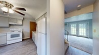 Located at 32 Nicole Dr in Spencerport, NY, this two-bedroom, one-bathroom home spans three floors, offering a well-distributed layout with dedicated spaces across each level. The entry-level floor provides the largest footprint, transitioning upward through two staircases to additional living areas above.

The kitchen features gray shaker-style cabinetry with light countertops, a single-basin sink, a dishwasher, a white electric range with overhead ventilation, and a full-size refrigerator. Wood-look vinyl flooring runs throughout the kitchen, and a window brings in natural light. The kitchen opens toward the living area, which is carpeted and notable for its French doors that provide outdoor access and fill the room with natural light. A wall-mounted AC unit and baseboard heating are present throughout the home.

Both bedrooms are carpeted and feature windows with views of the surrounding greenery, baseboard heating, and wall-mounted AC units. The primary bedroom includes a sliding closet. The bathroom is finished with mosaic tile flooring, white wall tiles, a vanity with storage, and a bathtub. A utility room completes the layout, providing additional functional space within the home.