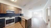 Located at 5710 Crescent Park E in the Playa Vista neighborhood of Los Angeles, this two-bedroom, one-bathroom residence offers a thoughtfully designed single-floor layout. Wood-look flooring flows consistently throughout the home, lending a cohesive, modern aesthetic.

The kitchen serves as a functional centerpiece, featuring a curved island with a quartz-style countertop, a professional-style pull-down faucet, dark cabinetry, stainless steel appliances including a gas range, dishwasher, and French door refrigerator, and pendant lighting overhead. The open sightlines connect the kitchen directly to the living room, which is bathed in natural light from large windows with vertical blinds and offers access to an outdoor area.

The primary bedroom is a well-proportioned retreat with wood-look flooring, soft neutral walls, and a window framing greenery outside. It connects to a dedicated walk-in closet equipped with built-in shelving and hanging space. The second bedroom mirrors the clean, light-filled character of the primary. The bathroom features hexagonal tile flooring, a dark wood vanity, open shelving, and a soaking tub with shower. Crown molding accents throughout add a refined finishing touch to this clean, contemporary residence.