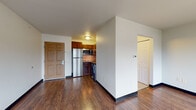 This single-floor unit offers a functional and cohesive layout designed for comfortable everyday living. Rich, dark hardwood-style flooring runs throughout the main living and bedroom areas, providing a warm and polished aesthetic that ties the space together.

The kitchen is efficiently designed and tucked into a dedicated alcove, featuring warm-toned wood cabinetry with a classic tile backsplash, stainless steel refrigerator, over-the-range microwave, and a washer/dryer unit — keeping laundry conveniently in-unit. The kitchen flows naturally into the open living area, which benefits from two generously sized windows that allow ample natural light to fill the room. A wall-mounted HVAC unit ensures year-round climate control. The bright, neutral-toned walls throughout contribute to an open, airy feel.

The bedroom is a well-proportioned space with a large window overlooking the surrounding area, a closet with a standard door, and a thermostat for individual temperature management.

The bathroom is finished with light ceramic tile flooring, a vanity featuring dark granite-style countertops and rich wood cabinetry, and a full tub with an arched, textured surround that adds a subtle decorative touch. Overall, the space is clean, practical, and thoughtfully appointed for modern residential living.