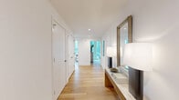 Located at 5 Cottage Place in White Plains, NY, this thoughtfully designed three-bedroom, two-bathroom residence offers a clean, modern aesthetic across a generous single-floor layout. Light-toned hardwood floors flow seamlessly throughout, complemented by crisp white walls and recessed lighting that create a bright, welcoming ambiance.

The entry hallway sets an elegant tone, featuring a built-in console and a framed mirror that lead guests into the open living areas. The living room is anchored by expansive floor-to-ceiling windows that frame sweeping urban views and flood the space with natural light. The adjacent dining room shares this dramatic window line, with a bold teal accent wall adding a vibrant focal point alongside the panoramic cityscape.

The kitchen is sleek and well-appointed, showcasing two-tone cabinetry, stainless steel appliances, a stylish tile backsplash, and a large center island with bar seating — ideal for both casual dining and entertaining. An in-unit laundry and four closets provide exceptional storage throughout.

The primary bedroom is generously sized with floor-to-ceiling windows offering urban vistas. All bedrooms are bright and well-proportioned. The bathrooms feature a clean, contemporary design with wood vanities, stone countertops, large-format tile floors, and a full soaking tub with shower combination.