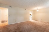 Located in Savannah, GA (31406), this single-floor residence offers a straightforward and functional layout across several well-defined living areas. The open living and dining space is generously sized, featuring plush carpeting, a textured ceiling, and multiple windows that bring in ample natural light with views of surrounding greenery. A pendant light fixture adds a subtle design touch to the dining area.

The galley-style kitchen is efficiently designed, offering rich wood cabinetry on both sides, laminate countertops, a double stainless steel sink, and white appliances including a coil-top range and a full-size refrigerator. The tile flooring in the kitchen provides a clean, durable surface.

The bedroom is a comfortable, carpeted room with a window allowing natural light in and direct access to the bathroom. The bathroom features warm wood vanity cabinetry, a wall-mounted mirror, tile flooring, and a full tub and shower combination with white tile surround and chrome fixtures.

Throughout the residence, neutral cream-toned walls, textured ceilings, and carpeted floors create a cohesive and understated aesthetic. The single-floor layout ensures easy accessibility, and the overall design prioritizes practical living in a convenient Savannah location.