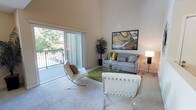 This single-story residence is thoughtfully designed to maximize comfort and functionality across its key living spaces. The living room serves as a standout feature, boasting dramatically tall ceilings that amplify the sense of openness. A large sliding glass door floods the room with natural light and provides direct access to a private balcony overlooking lush greenery. Soft carpeting anchors the space, which comfortably accommodates a seating arrangement centered around a glass coffee table.

The galley-style kitchen is efficiently laid out with light wood cabinetry, granite-style countertops, and hardwood-style flooring. Black appliances, including a refrigerator, electric range, microwave, and dishwasher, line both sides of the corridor, maximizing storage and workspace.

Two carpeted bedrooms offer comfortable retreats, each featuring windows that invite natural light. The primary bedroom includes a spacious sliding-door closet, while both rooms provide ample wall space. Two bathrooms serve the residence: one features hardwood-style flooring, a vanity with granite-style countertops, and a shower-tub combination, while the second bathroom also includes a tub and shower setup with chrome fixtures.