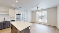 Located in Denver's Central Park neighborhood, this well-appointed 2-bedroom, 1-bathroom residence offers a thoughtfully designed single-level layout with contemporary finishes throughout. Light hardwood flooring flows consistently across all living areas, creating a cohesive and welcoming atmosphere.

The open-concept kitchen serves as a central hub of the home, featuring a striking two-tone cabinet design with crisp white upper cabinets and dark wood-grain lower cabinets, complemented by a white subway tile backsplash. A spacious center island with a quartz countertop provides additional prep space and seating. Stainless steel appliances, including a refrigerator, range, microwave, and dishwasher, complete the kitchen. The space flows seamlessly into the living area, which is brightened by large windows and equipped with a ceiling fan.

The primary bedroom offers generous proportions with corner windows that fill the room with natural light and views of the surrounding neighborhood. It connects directly to the full bathroom and a dedicated walk-in closet with wire shelving. The bathroom features classic white subway tile in the tub/shower surround, matte black fixtures, and a dark wood vanity. The second bedroom is equally well-lit, with a large window overlooking the exterior. Recessed lighting and clean, neutral walls round out this move-in-ready home.