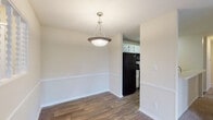 Located at 6300 Moseley Dixon Rd in Macon, GA, this single-floor residence offers a well-organized layout designed for comfortable everyday living. The entryway opens to a transition between the carpeted living area and the wood-look flooring that runs through the dining and kitchen spaces. The living room is generously sized, featuring plush carpeting, a ceiling fan, and French doors with an adjacent window that invite natural light and provide outdoor views. The dining area is defined by chair-rail molding and a pendant light fixture, and flows directly into the kitchen. The kitchen is equipped with white cabinetry, light countertops, and a full suite of black appliances including a refrigerator, range, and over-the-range microwave, along with wood-look flooring for easy maintenance. The bedrooms are carpeted and include ceiling fans and windows that bring in natural light, creating comfortable, restful spaces. Two bathrooms serve the unit; each features a white vanity with light countertops, a tub-shower combination, wood-look flooring, and clean, neutral finishes throughout. Warm beige tones and white trim are consistent across all rooms, giving the entire space a cohesive and bright aesthetic.