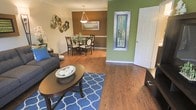 This two-story residence offers a thoughtfully designed interior that balances comfort and style. The main living area features rich hardwood flooring that flows seamlessly throughout, anchored by a plush seating arrangement set atop a bold blue patterned area rug. A dark wood oval coffee table serves as a centerpiece, adding warmth and definition to the space.

The open layout connects the living room directly to the dining area, which is highlighted by a pendant light fixture suspended above a round dining table with elegant chairs. Crown molding trims the ceiling, lending a refined architectural detail to the space. Earthy brown accent walls in the dining area contrast beautifully with a striking olive green wall near the entryway, where a decoratively framed mirror adds visual depth and dimension.

A white paneled door near the entry provides access to additional areas of the home, while wall art and sculptural décor elements contribute to the curated, expressive character of the interior. The overall ambiance is warm and inviting, with a lively color palette and cohesive design choices that make the space feel both lived-in and stylish. The two-floor layout offers additional living space beyond what is visible, suggesting a well-rounded and functional home.