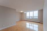 Located on the 8th floor at 195 Kennedy Road South in Brampton, Ontario, this one-bedroom, one-bathroom unit offers a well-organized layout across a single floor. Gleaming parquet wood flooring runs throughout the main living areas, adding warmth and a classic character to the space.

The open living and dining area is bright and airy, anchored by large floor-to-ceiling windows that frame expansive city views and allow generous natural light to fill the room. A sliding door leads out to a private balcony, extending the living space outdoors. Baseboard heating runs beneath the windows, ensuring comfort year-round.

The kitchen is fitted with sleek white cabinetry, dark granite countertops, a stainless steel refrigerator, and a stainless steel appliance suite, all set on durable tile flooring. A hallway connects the main living areas to the private quarters.

The bedroom is a comfortable size, featuring its own window with outdoor views, parquet flooring, and a closet. The bathroom is finished in a clean, contemporary style with white cabinetry, a full tub-shower combination with a sliding glass rod, and grey tile flooring. The overall ambiance of the unit is clean, functional, and well-lit, making efficient use of its thoughtfully designed floor plan.