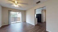 Located at 501 116th Ave N in Saint Petersburg, FL, this single-floor residence offers a thoughtfully laid-out living space with a clean, neutral aesthetic throughout. The open-concept living area is anchored by rich, dark wood-style flooring and features a ceiling fan with light fixture overhead, a textured ceiling, and a sliding glass door that leads to a private balcony, allowing natural light to fill the room and providing pleasant outdoor views. The kitchen is positioned adjacent to the living area via an open pass-through design, outfitted with white cabinetry, speckled countertops, black appliances including a refrigerator and electric range, an overhead exhaust hood, and a window that brings in additional natural light. A dedicated bedroom offers carpeted flooring, a window with blinds, and a reach-in closet with a built-in rod for ample storage. A second room with wood-style flooring also includes a closet and connects conveniently to the main living and kitchen areas. The full bathroom is well-appointed with a single-sink vanity featuring white cabinetry and a large mirror, a toilet, and a shower-tub combination. Throughout the unit, consistent neutral wall tones and crisp white trim create a cohesive, move-in-ready environment.