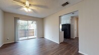 Located at 501 116th Ave N in Saint Petersburg, FL, this single-floor residence offers a thoughtfully laid-out living space with a clean, neutral aesthetic throughout. The open-concept living area is anchored by rich, dark wood-style flooring and features a ceiling fan with light fixture overhead, a textured ceiling, and a sliding glass door that leads to a private balcony, allowing natural light to fill the room and providing pleasant outdoor views. The kitchen is positioned adjacent to the living area via an open pass-through design, outfitted with white cabinetry, speckled countertops, black appliances including a refrigerator and electric range, an overhead exhaust hood, and a window that brings in additional natural light. A dedicated bedroom offers carpeted flooring, a window with blinds, and a reach-in closet with a built-in rod for ample storage. A second room with wood-style flooring also includes a closet and connects conveniently to the main living and kitchen areas. The full bathroom is well-appointed with a single-sink vanity featuring white cabinetry and a large mirror, a toilet, and a shower-tub combination. Throughout the unit, consistent neutral wall tones and crisp white trim create a cohesive, move-in-ready environment.
