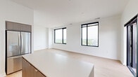 This thoughtfully designed two-bedroom, two-bathroom unit occupies a single floor and offers a clean, contemporary aesthetic throughout. Light-toned hardwood flooring runs continuously across the living spaces, reinforcing the unit's cohesive and modern character.

The open-concept kitchen and living area serves as the central hub of the unit. The kitchen is outfitted with gray wood-tone cabinetry, stainless steel appliances, a white quartz countertop, and a matching island with built-in storage — ideal for both meal preparation and casual dining. Track lighting above adds a functional yet stylish touch.

The living area benefits from two large black-framed windows that frame expansive views of the surrounding cityscape and tree canopy, filling the space with natural light.

The primary bedroom is a well-proportioned retreat featuring multiple large windows with elevated city views, and access to a walk-in closet outfitted with built-in shelving, hanging rods, and a dedicated shoe rack. The second bedroom is compact yet functional, with a black-framed window offering urban skyline views.

Both bathrooms maintain the unit's modern palette, with clean white walls, wood-tone vanities, and light tile flooring. Two hallways connect the rooms efficiently, and the overall layout is well-organized and easy to navigate.