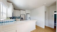 Located in Thousand Oaks, CA, this thoughtfully designed 2-bedroom, 1-bathroom single-floor home offers a clean, modern aesthetic throughout. Light wood-tone flooring runs continuously across the entire space, complementing the crisp white walls and recessed lighting that keep the interior feeling bright and airy.

The open-concept living area flows seamlessly into the kitchen, which serves as the clear focal point of the home. The kitchen is outfitted with white shaker cabinetry, a blue subway tile backsplash, quartz countertops, and a full suite of stainless steel appliances including a refrigerator with ice dispenser, range, microwave, and dishwasher. A peninsula with a matte black faucet provides additional workspace and casual seating. A stacked washer and dryer unit is conveniently integrated into the kitchen area.

Both bedrooms feature the same warm wood flooring, ceiling fans, and windows with blinds that admit natural light. The primary bedroom includes a closet with sliding panel doors. The bathroom is finished with a clean white palette, featuring a tub-shower combination enclosed by a sliding glass door with matte black framing. The overall ambiance of the home is modern, light-filled, and move-in ready.