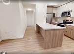 Unit 1208 at 49 Walnut St S is a modern high-rise condominium offering 710 square feet of thoughtfully designed living space across 3 bedrooms and 2 bathrooms. Light-toned laminate flooring flows consistently throughout, complementing the clean, neutral palette of white walls and warm wood-tone cabinetry found in every room.

The kitchen is a functional centerpiece, featuring a large island with a white quartz countertop, wood-grain base cabinetry, white upper cabinets, a subway tile backsplash, and a full suite of stainless steel appliances including a refrigerator, stove, microwave, and dishwasher.

Each of the three bedrooms benefits from large floor-to-ceiling windows that fill the rooms with natural light and offer impressive elevated views of Hamilton's downtown cityscape. The primary bedroom measures 110 square feet and includes a built-in wardrobe with wood-tone doors. The two bathrooms are finished with wood-grain vanities and white quartz countertops; one features a soaker tub and shower combo, while the other is a sleek half-bath with city views. Two hallways provide efficient circulation throughout the unit. The overall ambiance is clean, contemporary, and bright.