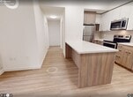 Unit 1208 at 49 Walnut St S is a modern high-rise condominium offering 710 square feet of thoughtfully designed living space across 3 bedrooms and 2 bathrooms. Light-toned laminate flooring flows consistently throughout, complementing the clean, neutral palette of white walls and warm wood-tone cabinetry found in every room.

The kitchen is a functional centerpiece, featuring a large island with a white quartz countertop, wood-grain base cabinetry, white upper cabinets, a subway tile backsplash, and a full suite of stainless steel appliances including a refrigerator, stove, microwave, and dishwasher.

Each of the three bedrooms benefits from large floor-to-ceiling windows that fill the rooms with natural light and offer impressive elevated views of Hamilton's downtown cityscape. The primary bedroom measures 110 square feet and includes a built-in wardrobe with wood-tone doors. The two bathrooms are finished with wood-grain vanities and white quartz countertops; one features a soaker tub and shower combo, while the other is a sleek half-bath with city views. Two hallways provide efficient circulation throughout the unit. The overall ambiance is clean, contemporary, and bright.