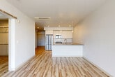 Located on the 18th floor at 201 Roy St in Seattle's Lower Queen Anne neighborhood, this modern one-bedroom, one-bathroom unit offers a thoughtfully designed open-concept layout. Light hardwood-style flooring runs throughout, complementing the clean white walls and creating a bright, cohesive aesthetic.

The combined living, dining, and kitchen area forms the heart of the unit. The contemporary kitchen features flat-front white cabinetry extending to the ceiling, stainless steel appliances including a refrigerator, range, and built-in microwave, and a peninsula with a gray quartz-style countertop and undermount sink. Pendant lighting adds a refined touch above the peninsula.

A welcoming entrance hall leads to the bedroom, den, and bathroom. The spacious bedroom benefits from floor-to-ceiling windows framing expansive city views, filling the room with natural light. The versatile den offers additional flexible space, while two closets provide ample storage. The bathroom includes a full tub-shower combination with brushed nickel fixtures and a vanity with matching cabinetry. A private balcony extends the living space outdoors. The unit's elevated position and large-format windows ensure abundant natural light and sweeping Seattle skyline views throughout.