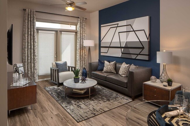 Living area with accent wall, wood like floors, double doors to patio, and typical furniture - Elle of Buckhead