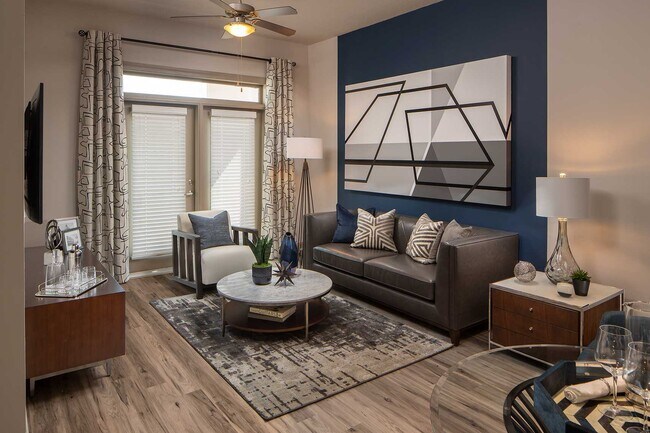 Sala de estar con pared decorativa, pisos de madera, puertas dobles al patio y muebles típicos. - Elle of Buckhead