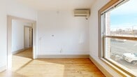 This single-floor unit offers a practical and comfortable layout with a variety of flooring and functional features throughout. The entryway welcomes you with warm hardwood floors and crisp white walls, leading into the main living areas. The kitchen is equipped with rich, deep-toned cabinetry, black appliances including a refrigerator, electric range, and built-in microwave, along with light countertops and hardwood-style flooring that contribute to a clean, organized workspace. The living areas continue the hardwood flooring theme, with large double-hung windows that invite natural light and offer views of the surrounding neighborhood. Wall-mounted split AC units are present in multiple rooms, ensuring year-round climate comfort. The bedrooms are carpeted for added warmth and comfort, each featuring neutral walls and windows that bring in natural light, with one offering a distinctive view of a green architectural dome nearby. Throughout the unit, consistent trim work, panel doors, and a neutral white palette create a cohesive and understated aesthetic. The space is well-suited for those seeking a functional, move-in ready home with classic details and practical amenities.