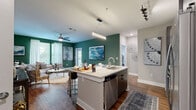 This well-appointed 2-bedroom, 2-bathroom residence at 2470 Cheshire Bridge Rd NE in Atlanta, Georgia offers a thoughtfully designed single-level layout. The open-concept kitchen is a standout feature, boasting two-tone cabinetry with white upper and dark wood-grain lower cabinets, a subway tile backsplash, stainless steel appliances, and a quartz-topped island with an undermount sink — ideal for cooking and entertaining. Rich hardwood-style flooring flows throughout the main living areas, complementing the kitchen and living room. The living room makes a bold impression with a deep green accent wall, large windows that invite natural light, and access to a private outdoor area. Both bedrooms are carpeted and feature ceiling fans, large windows with views of greenery, and a calm, neutral palette. The primary bedroom is generously sized with its own closet. The two bathrooms are finished with classic subway tile — one featuring a glass-enclosed walk-in shower with modern fixtures, and the other a full soaking tub. Two dedicated closets add practical storage throughout. The overall ambiance is modern yet comfortable, blending contemporary finishes with warm tones for an inviting atmosphere in the heart of Atlanta.