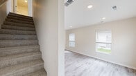 This two-story townhome in Pleasant Hill, Iowa offers a practical and modern layout spread across two well-proportioned floors. The main level features light luxury vinyl plank flooring throughout, anchored by a contemporary kitchen equipped with gray shaker-style cabinetry, granite-look countertops, stainless steel appliances including a refrigerator, electric range, and built-in microwave, as well as a stainless steel sink. A pantry with wire shelving provides generous storage space. Recessed lighting and natural light from blinds-fitted windows keep the main living area bright and welcoming. A carpeted staircase leads to the upper level, where multiple bedrooms are finished with plush carpet flooring and fitted with ceiling fans and window blinds that allow for views of the surrounding neighborhood. The bathroom on the upper floor includes a full soaking tub and shower combination with brushed nickel fixtures set in a clean white surround. Neutral wall tones throughout both floors create a cohesive, move-in-ready aesthetic. The home's efficient design makes excellent use of every square foot, delivering comfortable living spaces in a clean, contemporary style suited to the Pleasant Hill community.