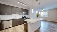 Located at 14700 Torrey Chase Blvd in Houston, TX, this thoughtfully designed one-bedroom, two-bathroom residence offers a modern aesthetic with high-quality finishes across a single floor. The open-concept kitchen is a standout feature, showcasing rich dark-wood cabinetry, a white subway tile backsplash, stainless steel appliances including a refrigerator, electric range, microwave, and dishwasher, and a granite-topped island with elegant pendant lighting overhead. Track lighting illuminates the kitchen, while light wood-style flooring extends throughout the main living areas, creating a bright and cohesive feel. The dining area benefits from natural light through a window and is accented by a ceiling fan. The bedroom offers a comfortable, carpeted retreat with a window fitted with blinds for privacy and natural light. A dedicated walk-in closet features multi-tier wire shelving and built-in lower storage shelves, providing ample organization. The bathrooms are well-appointed, with one featuring a soaking tub and shower combination with marble-style tile surround and chrome fixtures. Light wood flooring and dark vanity cabinetry with granite countertops carry the home's modern design language into the bathrooms. This residence combines contemporary style with practical functionality throughout.