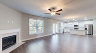 Located at 3940 Fence Rd NE in Auburn, Georgia, this three-story home offers generous living space across multiple well-appointed floors. The main level features an open-concept layout seamlessly connecting the living room, dining area, and kitchen. The kitchen is a standout, boasting white shaker cabinets, granite countertops, a central island, subway tile backsplash, and stainless steel appliances, all complemented by wood-look flooring and recessed lighting. The living area flows naturally to a large wood deck, offering serene views of mature surrounding trees. A separate formal dining room features a chandelier and a large window that fills the space with natural light. The upper floor hosts the primary bedroom, distinguished by a tray ceiling with crown molding and plush carpeting, alongside additional bedrooms with walk-in closets and well-appointed bathrooms featuring tub-shower combos and dark wood vanities. A dedicated laundry room adds everyday convenience. The lower level includes a basement and an attached garage with built-in shelving. Throughout, neutral tones, consistent hardwood-style flooring, and clean architectural lines create a cohesive and modern aesthetic suited for comfortable living.