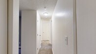 Located in University Place, Washington, this one-bedroom, one-bathroom residence offers a compact and efficient single-floor layout designed for comfortable everyday living. The living room serves as the heart of the home, featuring plush wall-to-wall carpeting, a striking stone-surround fireplace as the focal point, and a large window that invites natural light while offering views of the surrounding greenery. Baseboard heating runs along the walls, ensuring warmth throughout the space. The bedroom is a well-proportioned retreat with its own large window providing additional natural light and outdoor views, continued carpeted flooring, and direct access to a dedicated closet for convenient storage. The bathroom is clean and functional, equipped with a full tub and shower combination featuring chrome fixtures and a handheld showerhead. The kitchen, visible from the adjacent area, includes white cabinetry and a light hardwood-style floor, providing a bright and practical cooking space. Throughout the unit, textured ceilings and neutral wall tones create a consistent, understated aesthetic. The overall layout flows logically from the main living area through to the private bedroom and bathroom, making efficient use of the available space.