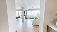 This sophisticated high-rise residence offers an impressive layout spanning a single floor, with 2 bedrooms, 6 bathrooms, multiple living areas, and a host of upscale finishes. Floor-to-ceiling windows run throughout the unit, flooding every room with natural light and framing sweeping panoramic views of the surrounding cityscape.

The chef's kitchen is a standout, featuring warm wood cabinetry, a striking marble-veined backsplash and countertops, a large center island with bar seating, stainless steel appliances, and light hardwood flooring that flows seamlessly into the adjoining dining and living areas. The dining space benefits from the same expansive windows and includes a sleek fireplace beneath a contemporary art piece.

The primary bedroom suite is generously proportioned, accompanied by a spa-caliber en-suite bathroom showcasing dark marble tile, a glass-enclosed walk-in shower, a freestanding soaking tub, and a refined vanity with granite countertops. Additional bathrooms echo the same high-end design with glass showers and polished tile work. Three walk-in closets provide extensive storage throughout.

Secondary living spaces offer flexibility for lounging or a home office. A dedicated laundry room includes cabinetry and a utility sink. Light hardwood flooring, recessed lighting, and dark-trimmed doors unify the home with a consistently modern, refined aesthetic.