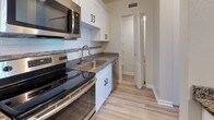 Located at 2738 Roosevelt Blvd in Largo, Florida, this single-floor unit offers a thoughtfully updated interior with a clean, modern aesthetic. The open layout is anchored by light wood-style flooring that flows seamlessly through the main living areas, creating a bright and cohesive feel.

The kitchen is a standout feature, equipped with stainless steel appliances including a range, microwave, refrigerator, and dishwasher. White shaker-style cabinetry pairs elegantly with granite countertops and a decorative tile backsplash. A peninsula counter with pendant lighting above connects the kitchen to the living area, offering a practical and stylish transition between spaces.

The living room is bright and welcoming, featuring a large window that invites natural light and provides a view of the outdoors. The front entry also benefits from an oversized window, further enhancing the airy atmosphere of the space.

The bedroom is carpeted for added comfort and includes a generously sized window that continues the theme of natural light throughout the unit. A louvered closet door adds a classic touch.

The bathroom is finished with a white shaker vanity, granite countertop, framed mirror, and updated fixtures, maintaining the consistent modern style found throughout the home. The overall design is clean, functional, and move-in ready.