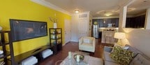 This single-floor residence offers a thoughtfully designed layout that balances style and functionality throughout. The living area makes a strong visual statement with a vibrant yellow accent wall, crown molding, rich hardwood flooring, and a ceiling fan overhead. Large windows with decorative drapes allow natural light to fill the room, while a glass door provides an inviting connection to the outdoors. The open-concept kitchen is a standout feature, showcasing dark espresso cabinetry, granite countertops, a white subway tile backsplash, and a full suite of stainless steel appliances. Pendant lighting and a breakfast bar with seating add to the kitchen's modern appeal. The bedroom continues the bold yellow accent wall theme, complemented by hardwood floors, a ceiling fan, and a window offering outdoor views. A walk-in closet provides generous storage. The bathroom features light tile flooring, a soaking tub with shower, and a dark-cabinetry vanity topped with granite. Completing the space is a dedicated in-unit laundry area equipped with a full-size washer and dryer alongside wire shelving for added storage convenience.