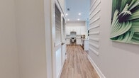 Located at 6 Country Squire Dr in Cromwell, Connecticut, this thoughtfully designed single-floor residence combines modern aesthetics with practical functionality. The layout flows seamlessly from room to room, all connected by a light-filled hallway with wood-look flooring and clean white trim work, including a distinctive slatted wall detail that adds architectural interest.

The kitchen serves as a central highlight, featuring crisp white shaker cabinetry extending to the ceiling, a classic subway tile backsplash, and stone countertops with subtle granite patterning. Stainless steel appliances, including a freestanding range and refrigerator, complement the space, while pendant lighting illuminates a peninsula with bar seating—ideal for casual dining or entertaining.

The bedroom is a serene retreat with plush carpeting, generous natural light from large windows, a walk-in closet with built-in shelving, and direct access to a private bathroom. The bathroom is designed with accessibility in mind, featuring grab bars, wood-look flooring, a stylish gray vanity with a white countertop, and a spacious layout.

An additional flexible room with accent wallpaper and natural light functions well as a home office or den. Throughout the residence, a neutral palette of soft grays and warm whites creates a cohesive, calm ambiance.