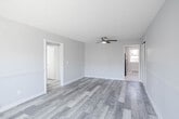 Located at 112 Atlantic Ave in Pleasantville, NJ, this single-floor, 3-bedroom, 1-bathroom home offers a clean and functional layout with consistent design elements throughout. The interior is finished with gray-toned wood-look flooring that flows seamlessly across the living spaces and bedrooms, complemented by light gray walls and crisp white trim for a fresh, modern feel.

The spacious primary bedroom is notably generous in size, featuring a ceiling fan with light fixture, a textured ceiling, and a wainscoting-style wall detail that adds architectural character. Additional bedrooms are well-proportioned, each equipped with ceiling fans and windows that bring in natural light, along with baseboard heating for year-round comfort.

The kitchen is outfitted with slate-blue cabinetry, a white subway tile backsplash, a stainless steel sink, and a bright window overlooking the outdoors. Light marble-style tile flooring completes the space with a clean, practical finish.

The bathroom is bright and neatly appointed with full white wall tiling, a tub-shower combination, pedestal sink, and a window for natural ventilation. Two hallways connect the rooms efficiently, and the overall layout, as seen in the dollhouse view, is compact yet well-organized, making excellent use of the available square footage throughout.