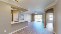 Located in Champions Gate, FL, this well-appointed 2-bedroom, 2-bathroom residence offers a thoughtfully designed single-floor layout with a warm, neutral color palette and wood-look flooring flowing throughout the main living areas. The open-concept great room seamlessly combines the living, dining, and kitchen spaces, creating an airy and functional hub for daily life. Crown molding and ceiling fans add refined detail, while a sliding glass door leads to a private balcony with outdoor views, filling the space with natural light. The kitchen is equipped with stainless steel appliances, including a range, over-the-range microwave, and refrigerator, complemented by warm wood cabinetry, a subway tile backsplash, and a breakfast bar peninsula for casual dining. A separate pantry provides additional storage. Both bedrooms are comfortably sized, each featuring ceiling fans, large windows with blinds, and ample closet space. The bathrooms are finished with tile flooring, dark wood vanities, and a tiled tub-shower combination. A dedicated in-unit laundry area with washer and dryer adds everyday convenience, while a utility room and multiple closets offer generous storage throughout.