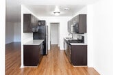 Located at 2175 Hudson Terrace in Fort Lee, New Jersey, this single-floor residence offers a thoughtfully updated interior with a clean, modern aesthetic throughout. Rich hardwood-style flooring extends across the living areas and bedrooms, providing a warm and cohesive look that ties the space together.

The kitchen is a standout feature, designed in a galley configuration with ample dark espresso cabinetry lining both sides, granite-style countertops, a white subway tile backsplash, and a full suite of stainless steel appliances including a gas range, microwave, refrigerator, and sink. The layout maximizes storage and counter space efficiently.

The living area is generously proportioned, with large windows that invite natural light and offer views of the surrounding neighborhood. A wall-mounted HVAC unit provides climate control, and the open layout offers flexible furniture arrangement options. The bedroom features its own window with natural light and closet access.

The bathroom is finished with a clean, neutral palette, showcasing a deep soaking tub with an overhead shower, a dark-cabineted vanity topped with granite counters, a large mirror, and decorative mosaic tile flooring. Brushed nickel fixtures add a refined touch throughout. This well-maintained residence combines functional design with updated finishes in a prime Fort Lee location.
