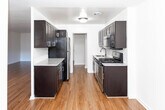 Located at 2175 Hudson Terrace in Fort Lee, New Jersey, this single-floor residence offers a thoughtfully updated interior with a clean, modern aesthetic throughout. Rich hardwood-style flooring extends across the living areas and bedrooms, providing a warm and cohesive look that ties the space together.

The kitchen is a standout feature, designed in a galley configuration with ample dark espresso cabinetry lining both sides, granite-style countertops, a white subway tile backsplash, and a full suite of stainless steel appliances including a gas range, microwave, refrigerator, and sink. The layout maximizes storage and counter space efficiently.

The living area is generously proportioned, with large windows that invite natural light and offer views of the surrounding neighborhood. A wall-mounted HVAC unit provides climate control, and the open layout offers flexible furniture arrangement options. The bedroom features its own window with natural light and closet access.

The bathroom is finished with a clean, neutral palette, showcasing a deep soaking tub with an overhead shower, a dark-cabineted vanity topped with granite counters, a large mirror, and decorative mosaic tile flooring. Brushed nickel fixtures add a refined touch throughout. This well-maintained residence combines functional design with updated finishes in a prime Fort Lee location.
