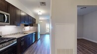 Located at 380 Mather St in Hamden, Connecticut, this thoughtfully designed single-floor residence offers a clean, contemporary aesthetic carried consistently throughout each space. Rich hardwood-style flooring runs throughout the unit, anchoring each room with warmth and visual continuity.

The kitchen is a standout feature, outfitted with deep navy and espresso-toned cabinetry, granite countertops with subtle veining, an undermount stainless steel sink, and a full suite of stainless steel appliances including a gas range, microwave, dishwasher, and refrigerator. Pendant and flush-mount lighting add to the kitchen's polished character.

The open living area is bright and welcoming, benefiting from large windows that invite natural light and offer views of the surrounding neighborhood. A glass-panel exterior door further enhances the connection to the outdoors. The layout flows naturally between the living space and kitchen, supported by a clean, neutral color palette on the walls.

The bedroom provides a quiet retreat with warm hardwood-style flooring and an adjoining area for added functionality. The bathroom is finished with a dark wood vanity, white countertop, framed mirror, and wood-look tile flooring, maintaining the refined design language of the rest of the unit. Overall, the space presents a modern, move-in-ready environment with quality finishes at every turn.
