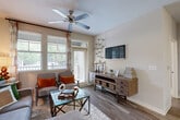 This thoughtfully designed 2-bedroom, 2-bathroom single-story residence in Fairburn, GA offers a comfortable and functional layout with a seamless open-concept flow. The living room is bright and welcoming, featuring wood-style flooring, a ceiling fan, and large windows with outdoor views that fill the space with natural light. An adjoining dining area with a bar-height table connects effortlessly to the kitchen, which boasts white cabinetry, granite countertops, a large island with seating, stainless steel appliances, and light tile flooring — ideal for both everyday cooking and entertaining. A stacked washer and dryer unit adds in-unit laundry convenience. The primary bedroom is generously sized with plush carpeting, multiple windows, a ceiling fan, and a dedicated walk-in closet with built-in wire shelving. The en-suite bathroom features tile flooring, a granite vanity, a soaking tub with shower, and a tall storage cabinet. The second bedroom and additional bathroom maintain the same quality finishes throughout. Two closets provide ample storage across the home. Neutral tones and consistent finishes create a cohesive, inviting ambiance throughout this well-rounded residence.