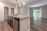 Located at 7201 Newport Ave in Norfolk, Virginia, this single-floor residence offers a well-designed layout with a seamless blend of style and functionality. The open-concept living and dining area is anchored by rich hardwood-style flooring and a sliding glass door that leads to a private balcony, filling the space with natural light and offering views of lush, tree-lined surroundings.

The kitchen is a standout feature, showcasing dark espresso cabinetry, granite countertops, a large central island with pendant lighting overhead, and a full suite of stainless steel appliances including a refrigerator, range, and microwave. The space flows naturally into the main living area, making it ideal for both everyday living and entertaining.

The bedrooms are carpeted for comfort, with neutral tones and generous closet space, including walk-in closets in select rooms. Large windows allow natural light to brighten these restful retreats. The bathroom is finished with stone-look tile flooring, a dark vanity with light countertops, and a glass-enclosed shower stall. Additional storage is provided through louvered closet doors visible in the common areas. The overall palette of warm neutrals and quality finishes creates a cohesive, inviting atmosphere throughout.