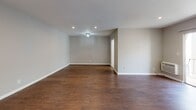 This single-floor unit is designed with a clean, functional aesthetic throughout. The living area is generously sized, featuring rich hardwood-style flooring and neutral gray-toned walls that create a calm, versatile backdrop. Recessed lighting illuminates the space, while a sliding glass door opens to a balcony, allowing natural light to filter in and providing views of the surrounding exterior. A wall-mounted air conditioning unit ensures year-round climate comfort.

The layout, as revealed by the floor plan, includes a well-defined separation between the living, sleeping, and kitchen areas. The kitchen is equipped with a stovetop range and provides ample room for meal preparation. Adjacent spaces offer additional storage and functional flow throughout the unit.

The bedroom continues the hardwood-style flooring and neutral palette, featuring a walk-in closet with dedicated storage space and recessed lighting overhead. A wall vent ensures proper air circulation.

The bathroom is finished with light marble-style tile flooring, a sliding-door shower and tub enclosure, a white vanity with storage, and a window that brings in natural light. The overall design of the unit is cohesive, practical, and move-in ready.