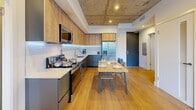 This contemporary apartment, located in TENTEN Downtown, offers a thoughtfully designed living space within 790 square feet. The unit features three bedrooms, including a spacious primary bedroom of 160 square feet, and two full bathrooms. The open-concept layout maximizes the use of space, creating a seamless flow between the living areas and the modern kitchen.

The kitchen boasts sleek cabinetry, stainless steel appliances, and a dining area, perfect for entertaining. Hardwood floors run throughout the main living spaces, while the bathrooms feature large-format tile and glass shower enclosures. The bedrooms are well-proportioned, with the primary bedroom offering city views through large windows.

Industrial-inspired elements, such as exposed concrete ceilings and columns, add character to the space while maintaining a clean, modern aesthetic. Built-in storage solutions and minimalist furnishings contribute to the apartment's efficient use of space. Recessed lighting and natural light from the windows create a bright, airy atmosphere throughout. This urban dwelling combines functionality with style, offering a comfortable living environment in a prime downtown location.