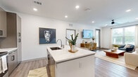 This thoughtfully designed 3-bedroom, 2-bathroom single-story home in Pensacola, Florida offers a clean, modern aesthetic with quality finishes throughout. The open-concept kitchen and living area serves as the heart of the home, anchored by a central island with a white quartz countertop, undermount sink, and seating for casual dining. The kitchen features dark wood cabinetry, stainless steel appliances, and a classic white subway tile backsplash. Wood-look flooring flows seamlessly from the kitchen into the bright living room, which is equipped with a ceiling fan and a large window that invites natural light and outdoor views. A hallway connects the living areas to the three bedrooms, each offering ample natural light through generously sized windows. The primary bedroom is a comfortable retreat with a ceiling fan, walk-in closet with built-in shelving and hanging rods, and serene outdoor views. The secondary bedrooms provide versatility, with one featuring a soothing accent wall. Both bathrooms include wood-toned vanities with white quartz countertops, undermount sinks, and wood-look flooring, maintaining the home's cohesive modern style.