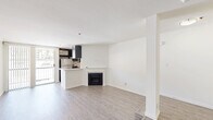 Located in the heart of West Hollywood at 1616 N Fuller Ave, Unit 404 is a thoughtfully laid-out studio that makes efficient use of its single-floor footprint. The open-plan living and kitchen area forms the core of the unit, characterized by crisp white walls, clean lines, and light gray wood-style flooring that runs throughout, lending a cohesive and modern aesthetic.

The living area is a standout feature, offering a generous elongated layout with a classic fireplace framed in white with a black surround, serving as a natural focal point. A subtle stepped platform detail adds architectural interest and helps define the space.

The galley-style kitchen is sleek and functional, featuring dark espresso cabinetry, stainless steel appliances including a full-size refrigerator and dishwasher, and a light-toned countertop with a double-basin sink. Recessed lighting illuminates the workspace efficiently.

A walk-in closet provides notable storage capacity with multiple hanging rods and built-in shelving along the walls—a practical feature for a studio unit.

The bathroom is clean and straightforward, finished in white tones with wood-style flooring consistent with the rest of the unit. Overall, the space offers a bright, minimalist ambiance suited for urban living.