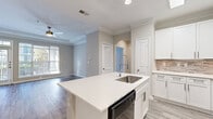 Located at Northlake Heights in Atlanta, GA, this well-appointed 2-bedroom, 2-bathroom single-floor home offers a thoughtfully designed layout with modern finishes throughout. The open-concept kitchen serves as the heart of the home, showcasing crisp white shaker cabinetry, a stone tile backsplash, quartz countertops, a center island with an undermount sink and pro-style faucet, and a full suite of stainless steel appliances. The kitchen flows seamlessly into the living area, which features hardwood-style flooring, crown molding, and a ceiling fan. The primary bedroom is generously sized, highlighted by a distinctive tray ceiling, crown molding, natural light from large windows, and its own walk-in closet with wire shelving. The second bedroom is carpeted, bright, and includes its own closet. The primary bathroom offers a dual-sink vanity with white cabinetry, quartz countertops, large mirrors, and stylish lighting. The second bathroom features a tiled tub-shower combination with a mosaic accent border. Additional conveniences include an in-unit laundry area and a hallway connecting all rooms. Neutral tones and consistent finishes create a cohesive, move-in-ready aesthetic throughout.