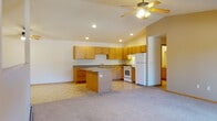 Located at 3560 Willow Dr in Plover, Wisconsin, this single-floor home offers a practical and comfortable layout designed for everyday living. The open-concept kitchen and living area serves as the heart of the home, featuring warm honey-toned wood cabinetry, granite-look countertops, a central island with additional storage, tile flooring, and a full suite of white appliances including a range, dishwasher, and refrigerator. Recessed lighting and ceiling fans throughout keep the space bright and well-ventilated. The spacious living area transitions seamlessly from the kitchen, with soft carpeting underfoot and a ceiling fan overhead. Bedrooms are carpeted and generously sized, with windows that bring in natural light and baseboard heating for year-round comfort. The home includes two bathrooms — one featuring a walk-in shower with tile flooring and wood cabinetry, and another full bathroom with a vanity, large mirror, and tile floors. A dedicated laundry room houses a full-size washer and dryer alongside wire shelving for added storage. A carpeted staircase with a wood handrail and ceiling fan provides access to additional levels. Clean, neutral finishes throughout give this home a move-in ready feel.