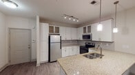 This single-floor residence at 4317 Millis Rd in Greensboro, NC offers a thoughtfully designed layout with contemporary finishes throughout. The open-concept living and kitchen area is anchored by a well-equipped kitchen featuring crisp white shaker-style cabinetry with brushed nickel hardware, granite countertops, and a full suite of stainless steel appliances including a refrigerator, electric range, built-in microwave, and dishwasher. A peninsula with a double undermount sink and pendant lighting adds both functionality and style, while track lighting overhead ensures ample illumination. Wood-look flooring runs throughout the main living areas, creating a cohesive and easy-to-maintain aesthetic.

The bedrooms are carpeted for comfort, each featuring neutral walls, windows with blinds that invite natural light and outdoor views, and ceiling fans in select rooms. The bathrooms are finished with granite-topped vanities and light wood-look tile flooring. One bathroom includes a tub-shower combination with grab bars and a light blue vanity, adding a distinctive touch. The overall ambiance is clean, modern, and move-in ready, with a neutral palette that complements a variety of décor styles.