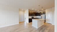 Located at 1000 New Holland Way NE in Gainesville, GA, this well-appointed 2-bedroom, 2-bathroom residence offers a thoughtfully designed single-level layout with modern finishes throughout. The open-concept kitchen and living area serves as the heart of the home, showcasing dark espresso cabinetry, granite countertops, a white subway tile backsplash, and a full suite of stainless steel appliances. A large central island with an integrated sink and pendant lighting adds both functionality and style, while light wood-style flooring flows seamlessly throughout the main living areas. The spacious primary bedroom features plush carpeting, a ceiling fan, and ample natural light from multiple windows. A generously sized walk-in closet with wire shelving provides excellent storage. The second bedroom also features soft carpeting and a ceiling fan. Both bathrooms are finished with clean, neutral tilework, including a tiled tub-shower surround in the full bath. A private balcony extends the living space outdoors, offering open views of lush greenery and the surrounding Gainesville landscape. Two dedicated closets throughout the home ensure practical storage solutions, completing this functional and attractive residence.