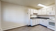 Located at 509 18th St in Greeley, Colorado, this single-floor, 2-bedroom, 1-bathroom unit offers a practical and efficient layout. The kitchen is well-equipped with white cabinetry providing ample storage, dark countertops, a built-in sink, a white electric range, over-the-range microwave, and a full-size refrigerator. Durable wood-look vinyl flooring and a skylight-style overhead fixture give the kitchen a clean, functional feel. A baseboard heating system is present throughout the unit. The living and dining areas flow naturally from the kitchen, creating an open and connected common space. Both bedrooms feature neutral carpet flooring, textured ceilings, built-in closets with sliding doors, and baseboard heating. The primary bedroom includes a built-in desk or shelf area with a mirror, adding a useful built-in feature. The second bedroom offers a window with natural light and an additional closet. The bathroom is outfitted with a full tub and shower combo, white tile surround, a classic mosaic tile floor, and chrome fixtures. The unit also includes four closets and a hallway, offering notable storage throughout. Overall, the unit presents a straightforward, well-organized floor plan suited for comfortable everyday living.