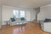 Located on Coolidge Highway in Oak Park, Michigan, this two-story home offers a well-organized layout across both levels. The main floor features warm hardwood flooring throughout the living and dining areas. The living room is positioned near the front entry, benefiting from natural light through large windows dressed with vertical blinds, offering views of the surrounding greenery. A carpeted staircase leads to the upper level directly from this space.

The dining area is a standout on the main floor, featuring a large floor-to-ceiling mirror wall that visually expands the room, complemented by a ceiling fan with integrated lighting and crown molding details. The kitchen is equipped with dark countertops, wood-framed cabinetry, a gas range, and a full-size refrigerator, with tile flooring and a window providing natural light.

Upstairs, the bedrooms are carpeted and well-proportioned, each offering natural light through sizable windows with vertical blinds. The primary bedroom provides ample space, while a second bedroom offers flexibility. The full bathroom features white tile flooring, tiled walls around the tub-shower combination, and a window for ventilation.