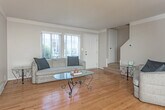 Located on Coolidge Highway in Oak Park, Michigan, this two-story home offers a well-organized layout across both levels. The main floor features warm hardwood flooring throughout the living and dining areas. The living room is positioned near the front entry, benefiting from natural light through large windows dressed with vertical blinds, offering views of the surrounding greenery. A carpeted staircase leads to the upper level directly from this space.

The dining area is a standout on the main floor, featuring a large floor-to-ceiling mirror wall that visually expands the room, complemented by a ceiling fan with integrated lighting and crown molding details. The kitchen is equipped with dark countertops, wood-framed cabinetry, a gas range, and a full-size refrigerator, with tile flooring and a window providing natural light.

Upstairs, the bedrooms are carpeted and well-proportioned, each offering natural light through sizable windows with vertical blinds. The primary bedroom provides ample space, while a second bedroom offers flexibility. The full bathroom features white tile flooring, tiled walls around the tub-shower combination, and a window for ventilation.