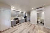 Located at 888 Fourth St in Santa Rosa, California, this thoughtfully designed studio unit makes efficient use of its single-floor layout. The open-plan living, dining, and kitchen area forms the heart of the space, with light wood-tone flooring flowing seamlessly throughout, creating a warm and cohesive atmosphere. Recessed lighting and a window allowing natural light and views of surrounding greenery further brighten the interior.

The kitchen is well-appointed with grey shaker-style cabinetry extending from floor to ceiling, offering ample storage. Stainless steel appliances include a range with oven, dishwasher, and refrigerator, complemented by light countertops and a single-basin sink. A range hood is integrated neatly above the stove.

The living area provides a comfortable, open retreat, with neutral wall tones and additional natural light from a second window. Two closets offer generous storage solutions within the unit, and a dedicated laundry area adds everyday convenience.

The bathroom features grey tile flooring, a vanity with under-sink cabinetry, a wall-mounted mirror, overhead lighting, and grab bar accessibility features. A wall-mounted mini-split unit provides climate control throughout the space. Clean finishes and a consistent grey-and-white palette give this unit a modern, move-in-ready appeal.